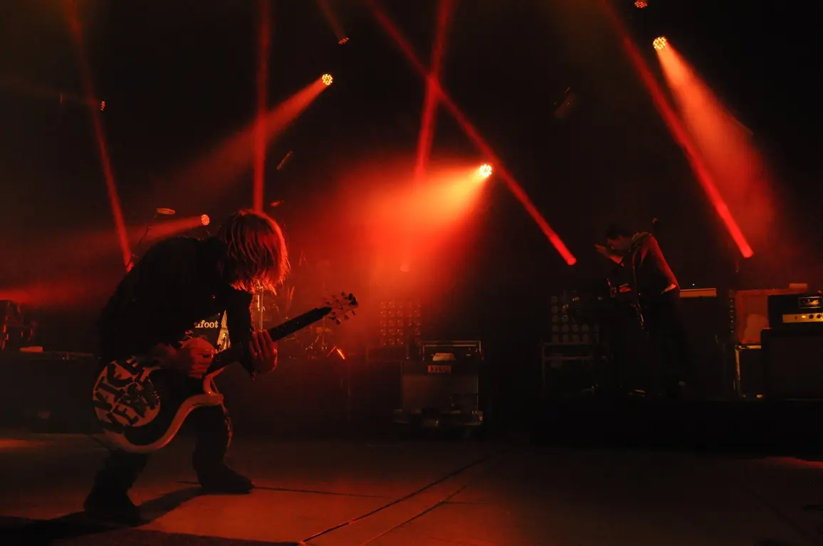 A band performing on stage. The lighting is very red