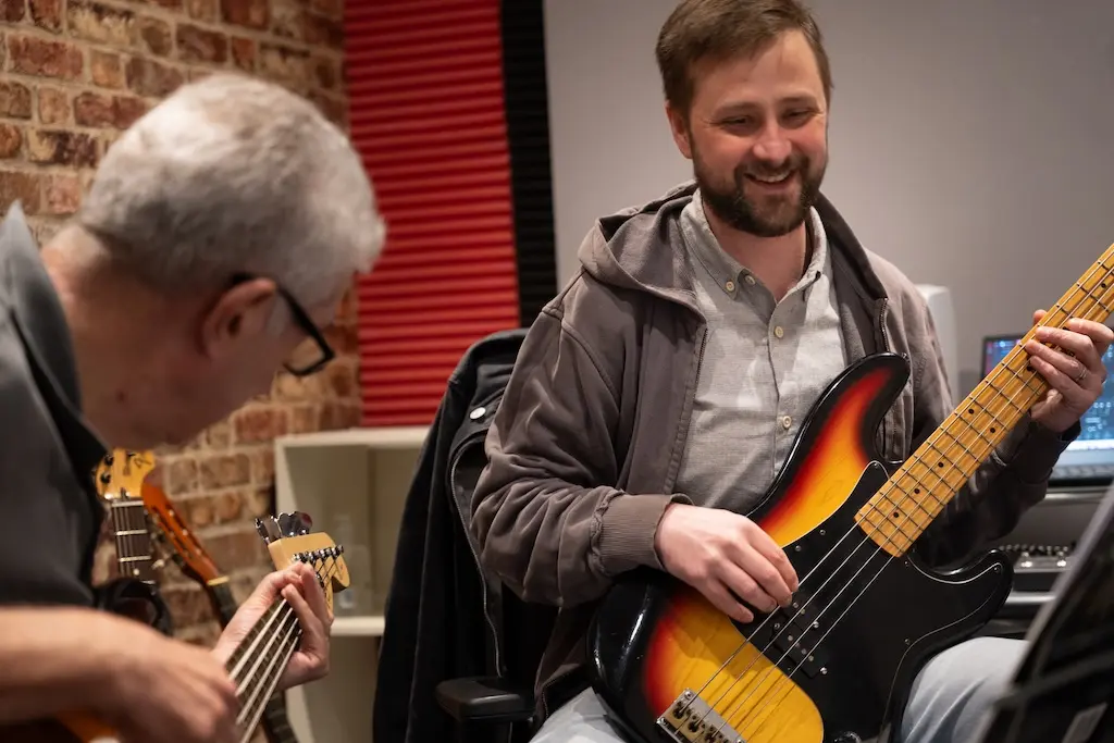 Two people holding bass guitars