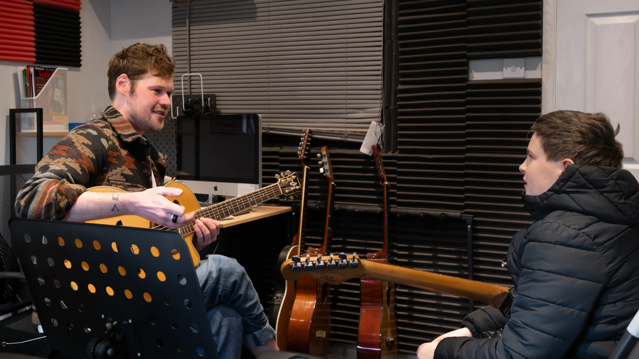 Two people holding guitars but not playing. Just talking.