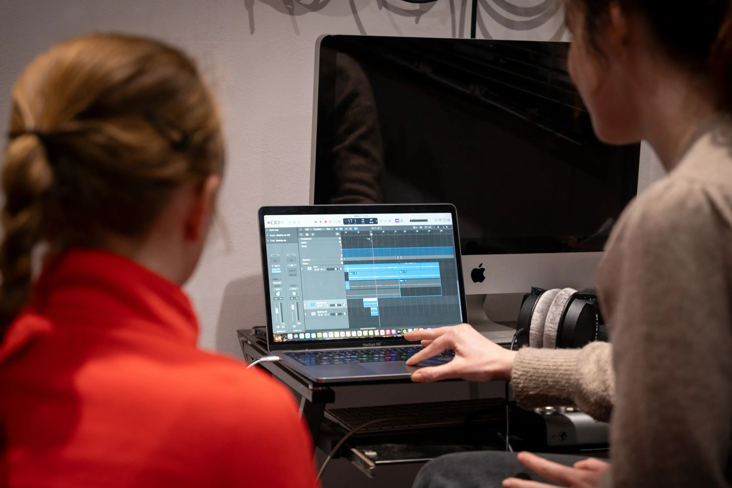 Two people sat at a computer using music editing software together